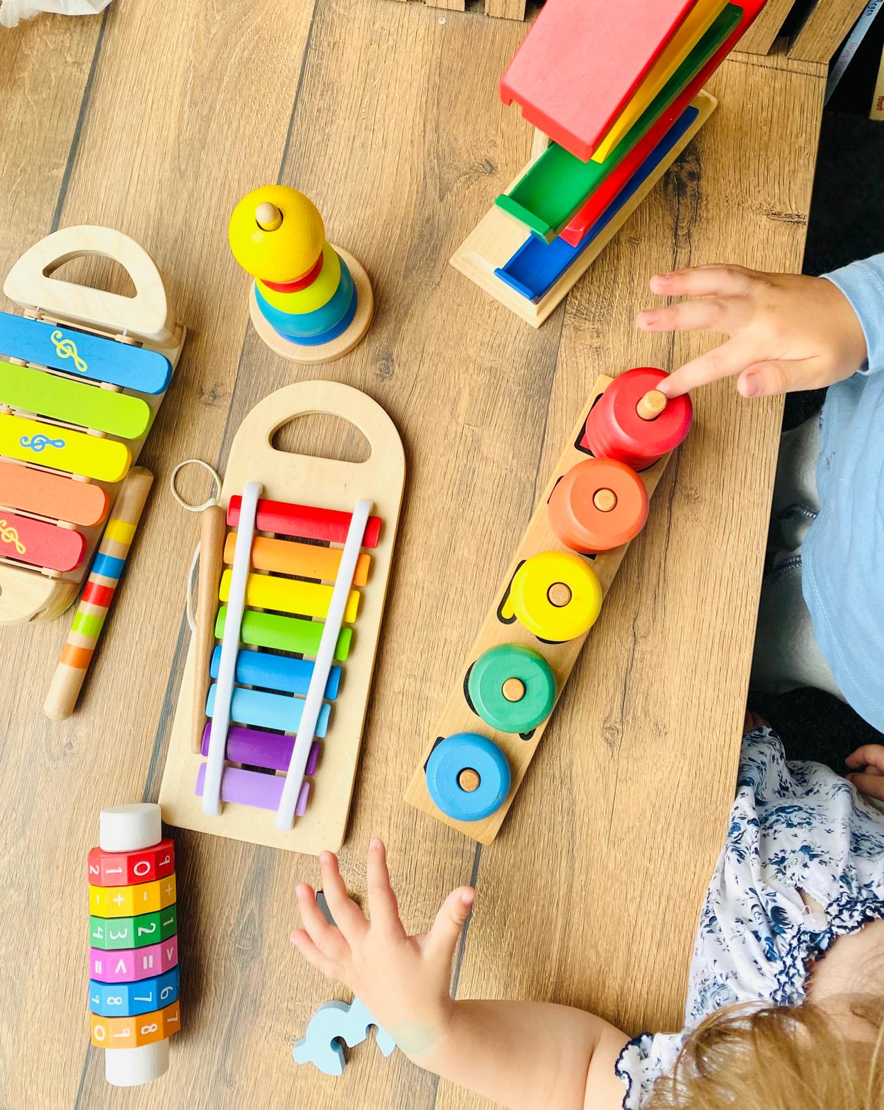 Kinderhände spielen mit buntem Holzspielzeug